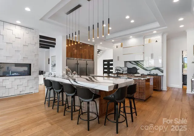 a kitchen with stainless steel appliances kitchen island granite countertop a table chairs sink and cabinets