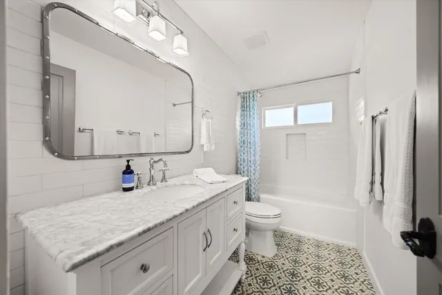 a bathroom with a granite countertop sink a toilet a mirror and shower