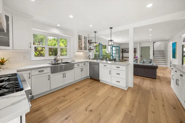 a large kitchen with stainless steel appliances lots of white cabinets and wooden floors