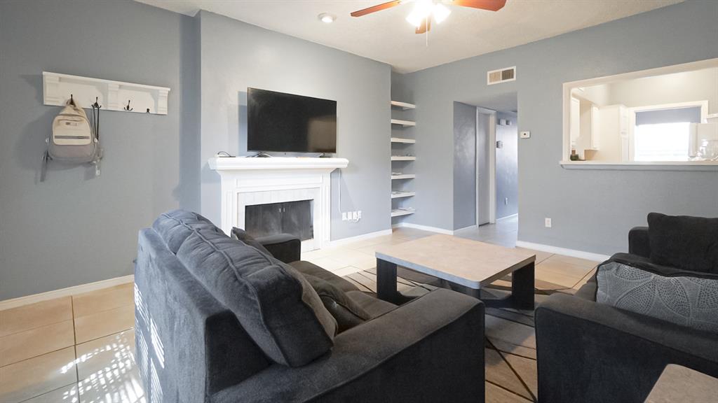 12921 Abrams Road, Unit 505 Dallas, TX 75243 - Photo 6 of 24 Living room with light tile patterned floors, a fireplace, and a ceiling fan