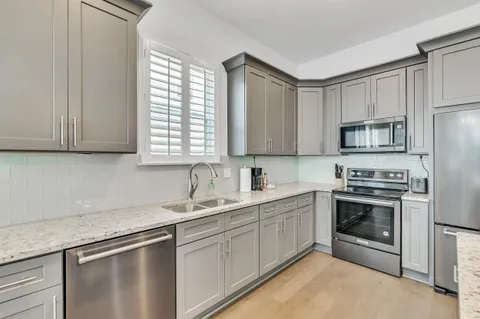 a kitchen with cabinets stainless steel appliances a sink and a window