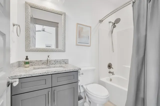 a bathroom with a granite countertop sink toilet a mirror a vanity and shower