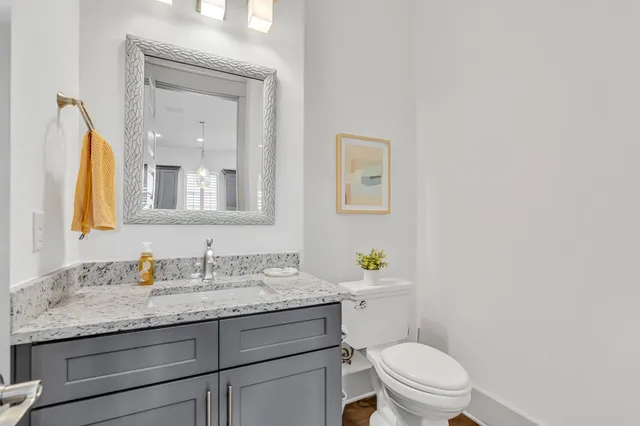 a bathroom with a granite countertop toilet sink and mirror