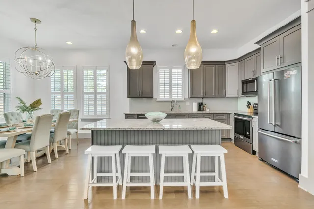 a kitchen with stainless steel appliances kitchen island granite countertop a dining table chairs and white cabinets