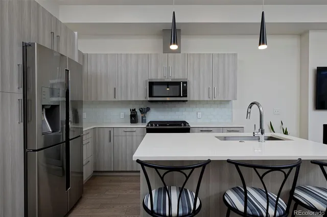 a kitchen with stainless steel appliances a refrigerator a stove a sink and chairs