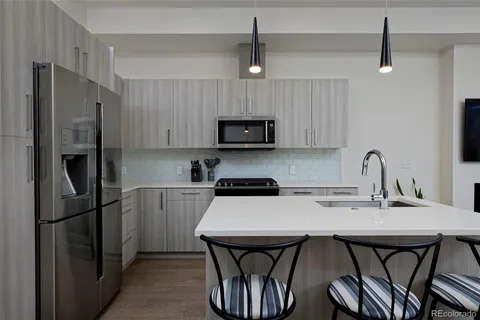 a kitchen with stainless steel appliances a refrigerator a stove a sink and chairs