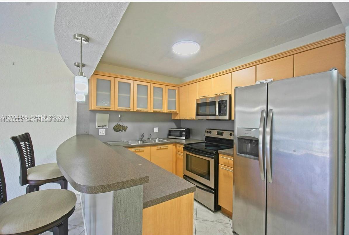 7401 Southwest 82nd Street, Unit 207S Miami, FL 33143 - Photo 3 of 15 a kitchen with stainless steel appliances granite countertop a refrigerator a stove a sink a dining table and chairs with wooden floor