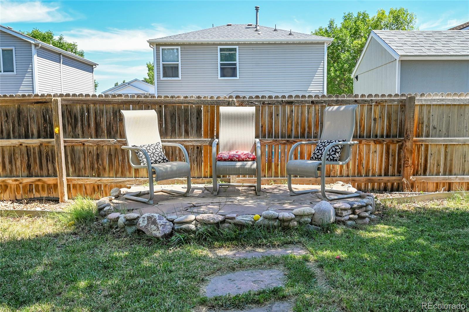 1489 Hummingbird Circle Brighton, CO 80601 - Photo 27 of 46 a view of a backyard with table and chairs and wooden fence
