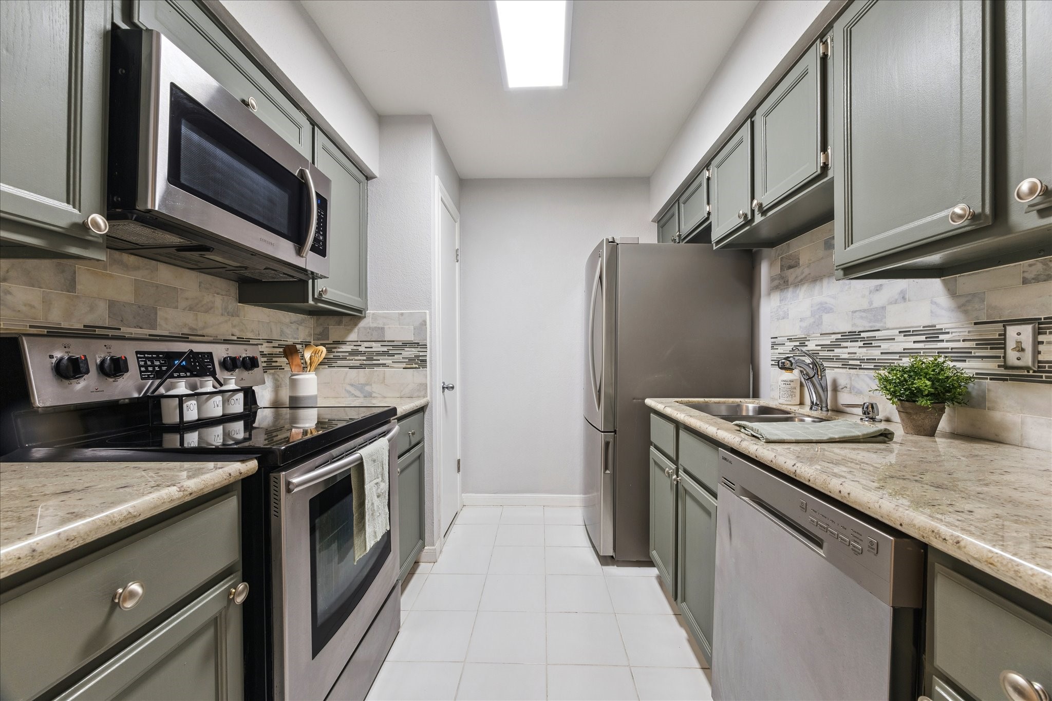 1201 Bering Drive, Unit 100 Houston, TX 77057 - Photo 10 of 20 a kitchen with stainless steel appliances granite countertop a sink stove and microwave