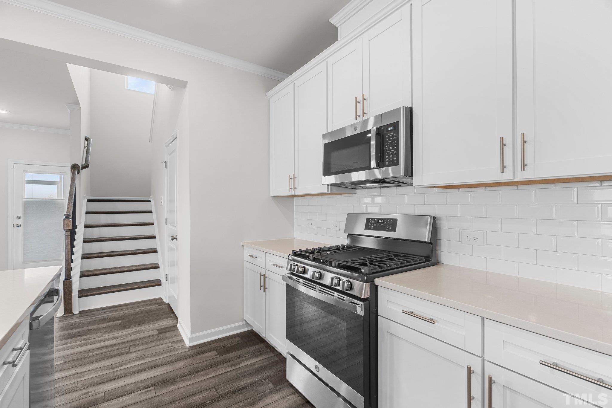5060 Tura Street Raleigh, NC 27610 - Photo 20 of 50 a kitchen with granite countertop a stove a microwave and wooden floor