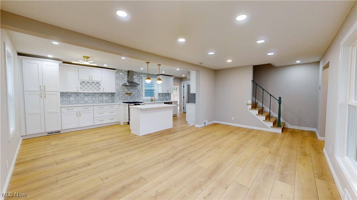 5252 Spencer Road Cleveland, OH 44124 - Photo 2 of 33 Kitchen featuring a center island, hanging light fixtures, wall chimney exhaust hood, light wood-type flooring, and white cabinetry