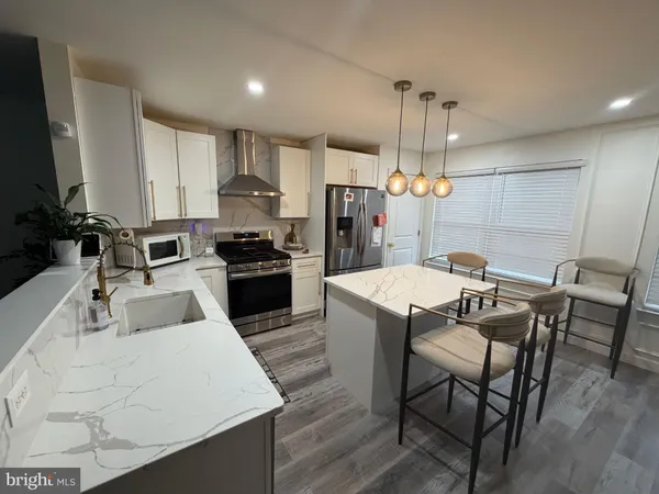 a kitchen with kitchen island a dining table chairs stainless steel appliances and cabinets
