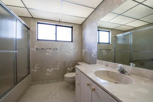 a bathroom with a granite countertop sink a toilet and shower