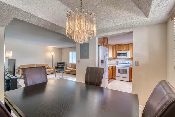 a living room with furniture a chandelier a large window and wooden floor