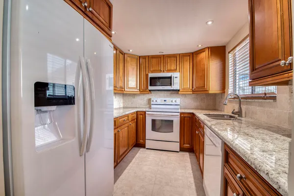 a kitchen with stainless steel appliances granite countertop a stove a sink and a microwave