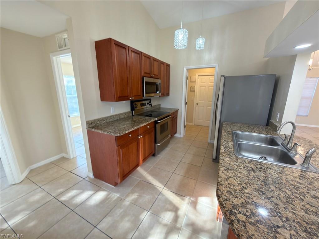 2513 48th Street Southwest Lehigh Acres, FL 33976 - Photo 19 of 22 a kitchen with stainless steel appliances granite countertop a sink stove and refrigerator