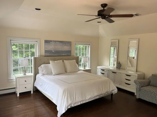 a bedroom with a bed couches and a flat tv screen on dresser