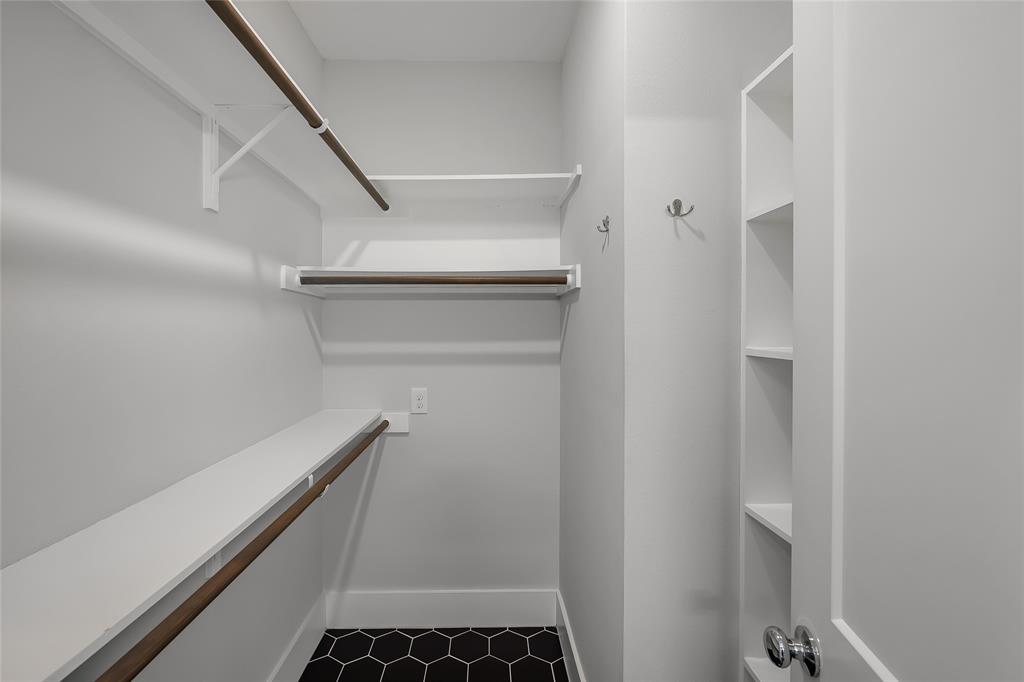 2821 Castro Street, Unit 1 Austin, TX 78702 - Photo 14 of 21 Walk-in closet featuring hexagonal black tile flooring, white shelving, dark wood-finish rods, and built-in vertical storage cubbies