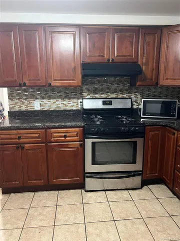 a kitchen with granite countertop a stove top oven and cabinets