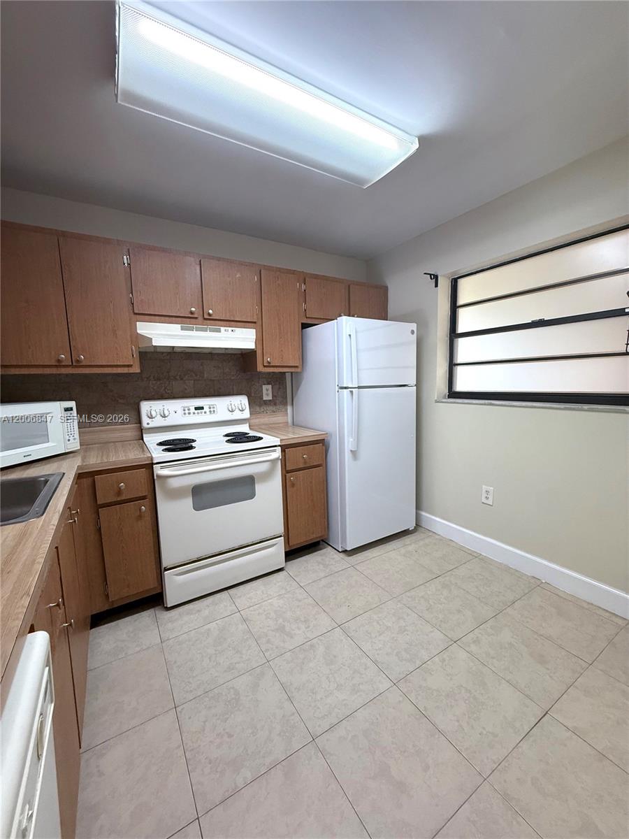 10835 Southwest 112th Avenue, Unit 306 Miami, FL 33176 - Photo 12 of 19 a kitchen with a stove a sink and a refrigerator