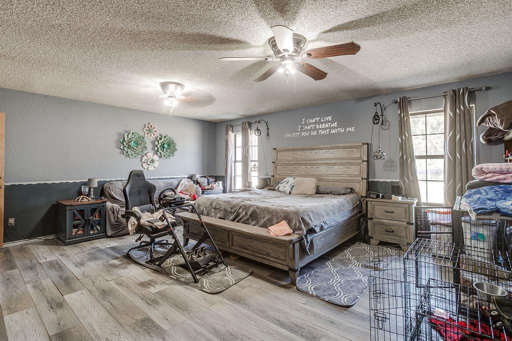 4763 Blue Flat Road Gordon, TX 76453 - Photo 12 of 40 a bedroom with a bed a chandelier and dresser