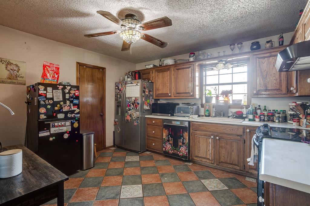 4763 Blue Flat Road Gordon, TX 76453 - Photo 8 of 40 a kitchen with stainless steel appliances granite countertop a refrigerator a sink dishwasher a dining table and chairs with wooden floor