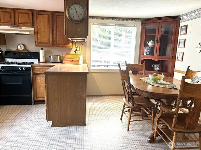 a kitchen with granite countertop a table chairs stove and cabinets