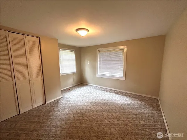 a view of an empty room with window and closet area