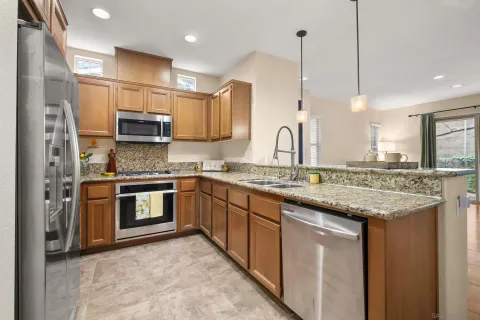 a kitchen with kitchen island granite countertop a sink cabinets and stainless steel appliances