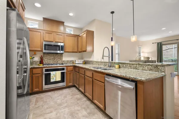 a kitchen with kitchen island granite countertop a sink cabinets and stainless steel appliances