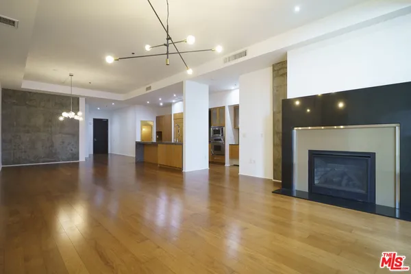 an empty room with wooden floor fireplace and windows