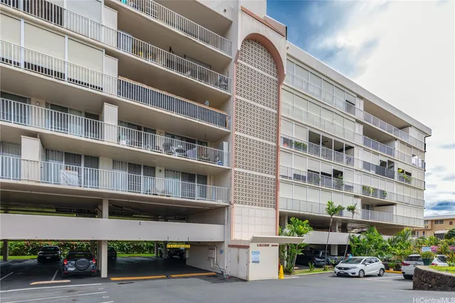 a front view of a building with lot of cars and trees