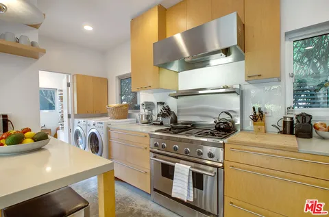 a kitchen with stainless steel appliances a stove a sink dishwasher and white cabinets with wooden floor