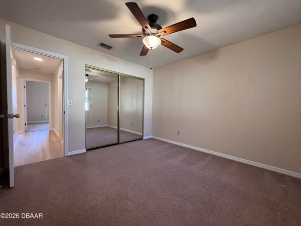 an empty room with closet and a ceiling fan