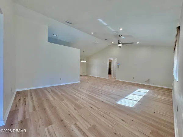an empty room with wooden floor cabinet and windows