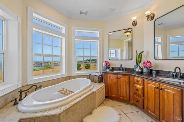 a bathroom with a tub a sink a mirror and a window