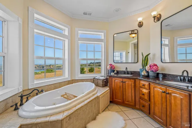 a bathroom with a tub a sink a mirror and a window