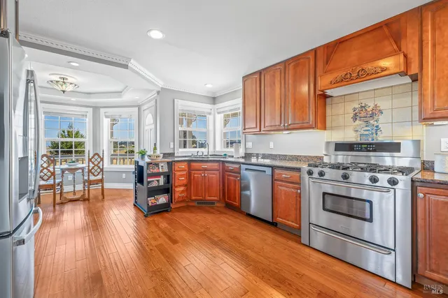 a kitchen with stainless steel appliances wooden floors and wooden cabinets