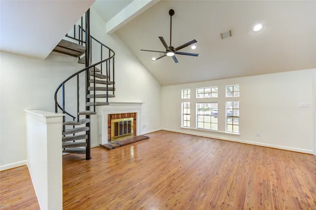 a view of an empty room with wooden floor fireplace and a window