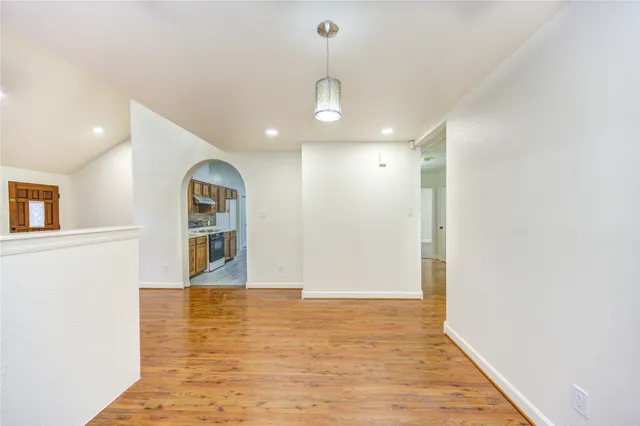 a view of an empty room with wooden floor and windows