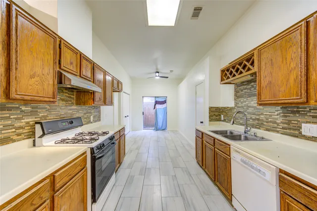 a kitchen with stainless steel appliances a sink dishwasher stove refrigerator and cabinets