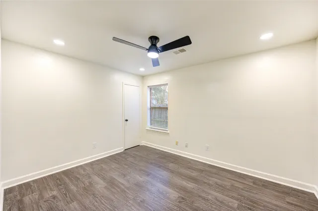 an empty room with wooden floor and ceiling fan