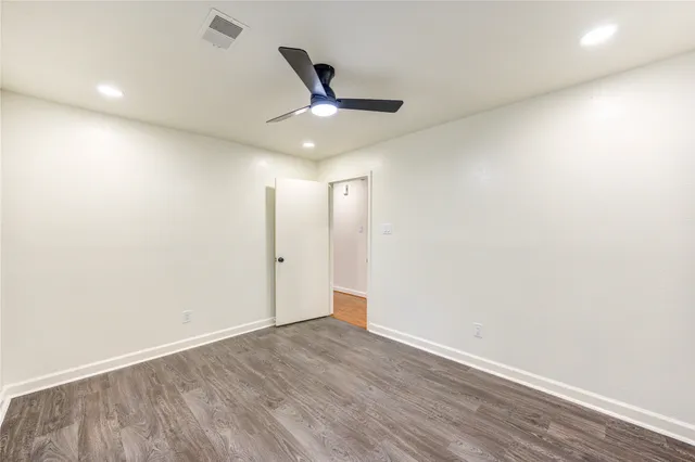 an empty room with wooden floor and ceiling fan