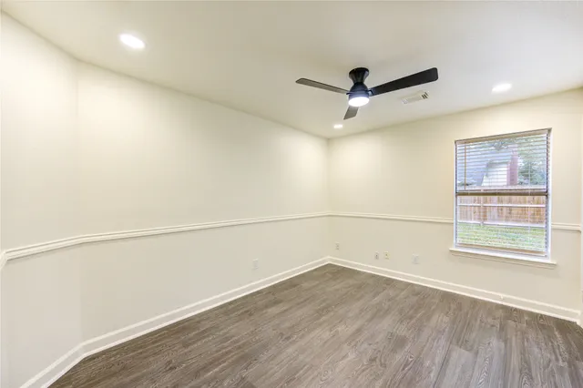 an empty room with wooden floor and ceiling fan