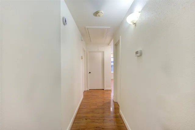 a view of a hallway with wooden floor and a bathroom