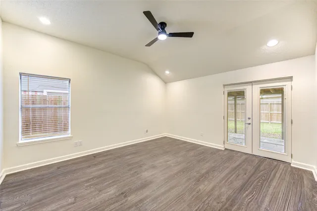an empty room with wooden floor ceiling fan and windows