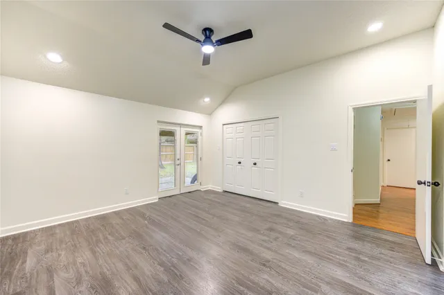 an empty room with wooden floor ceiling fan and windows