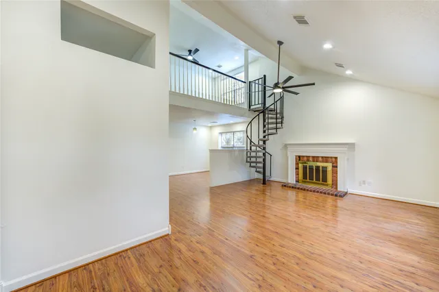 a view of empty room with wooden floor and fan