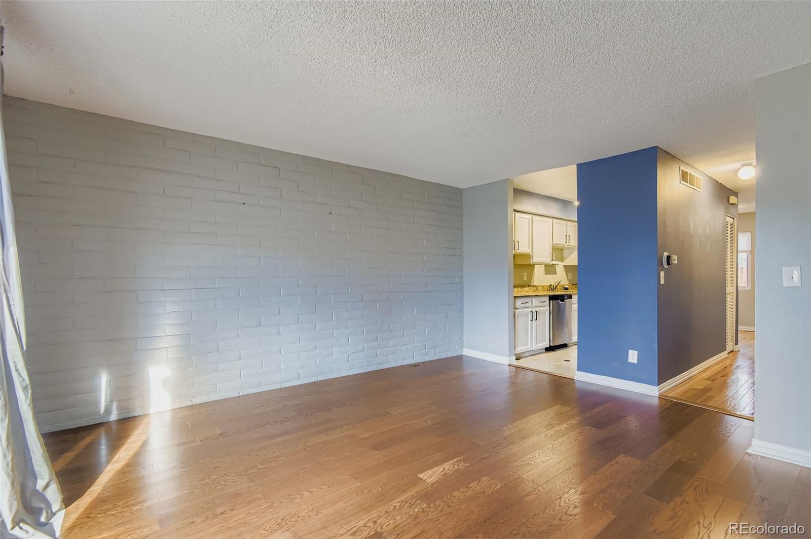 1060 South Parker Road, Unit 25 Denver, CO 80231 - Photo 14 of 26 a view of an empty room with wooden floor and a kitchen