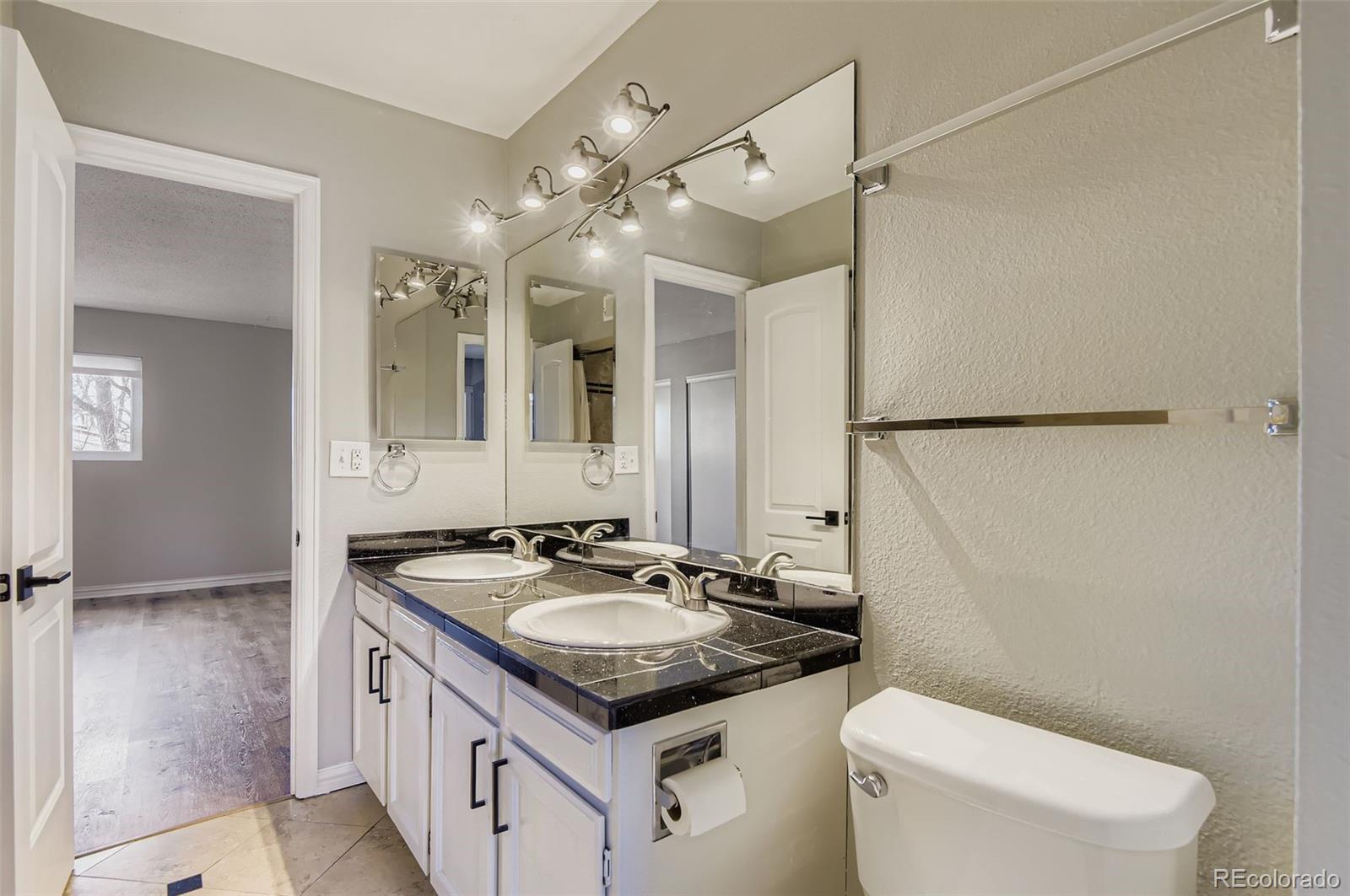 1060 South Parker Road, Unit 25 Denver, CO 80231 - Photo 20 of 26 a bathroom with a granite countertop sink a toilet a mirror and shower